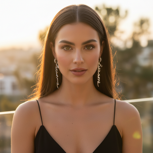Woman wearing a black dress and silver earrings with a blurred outdoor background