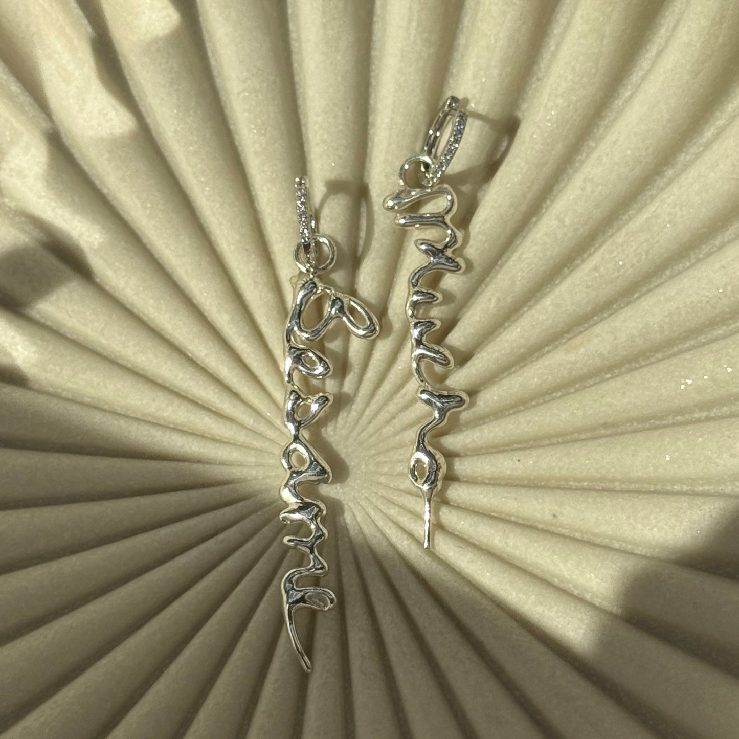 Silver earrings on a textured beige surface