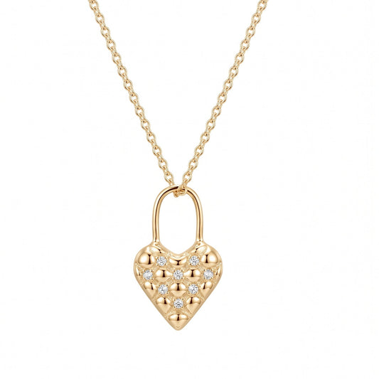 A gold quilted heart-shaped pendant necklace paved with small clear stones, suspended from a delicate silver chain against a solid white background.
