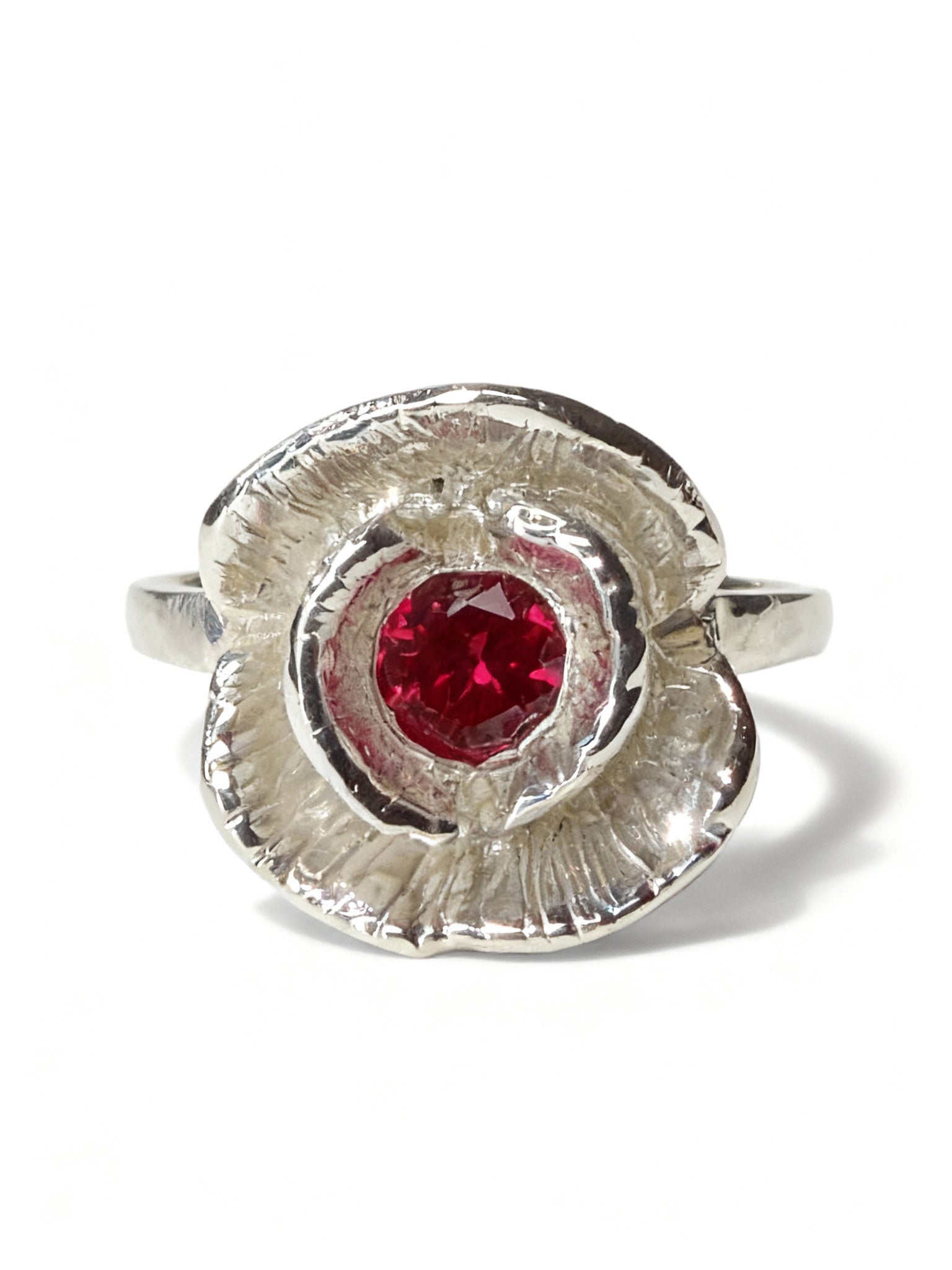 Silver ring with a red ruby on a white background