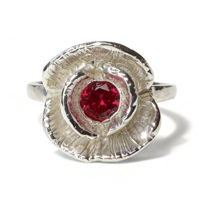 Silver ring with a red ruby on a white background