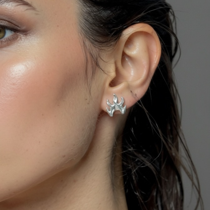 Close-up of a woman wearing a silver flame earring against a neutral background