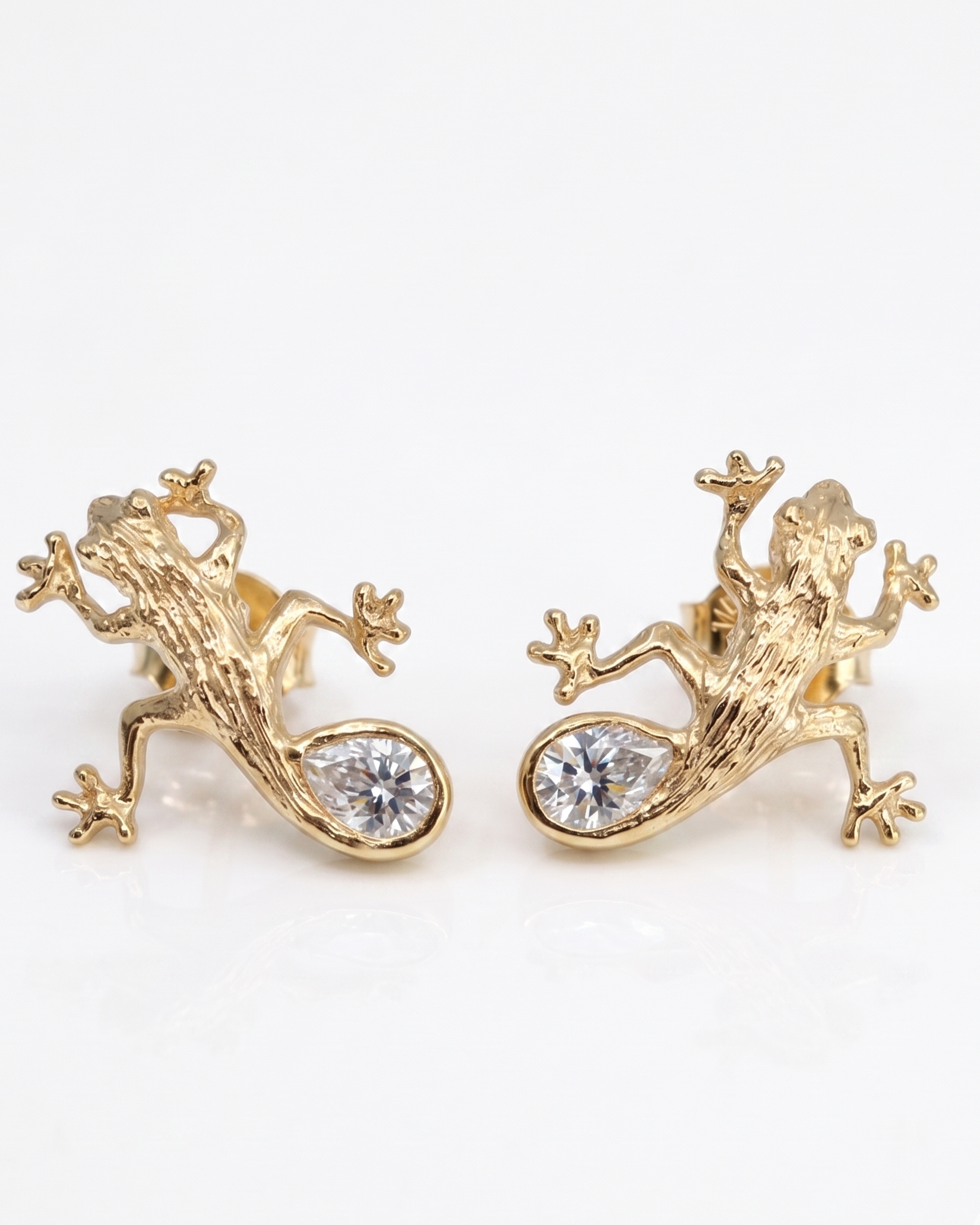 Luxury Solid sterling silver gecko-shaped earrings, 14K gold-plated, with a pear-shaped white moissanite stone. The earring is crafted by hand and showcased on a cactus plant.