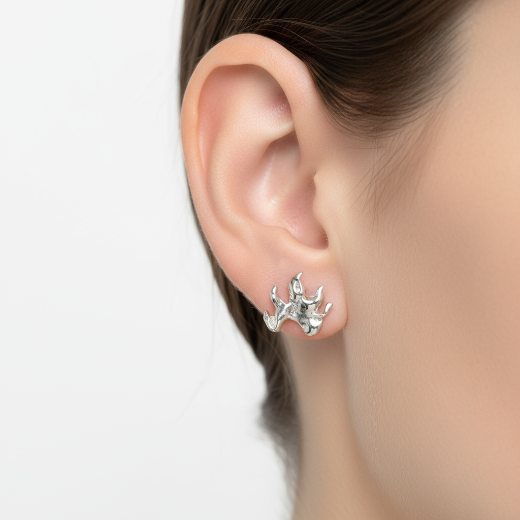 Silver flame-shaped earrings worn by a person on a white background