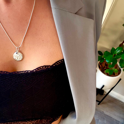 Person wearing a silver and sapphire necklace with a large moon pendant