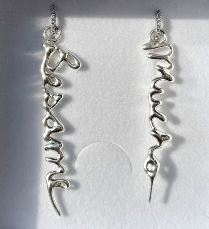 Silver earrings with 'Besame' and 'Mucho' inscriptions on a white background
