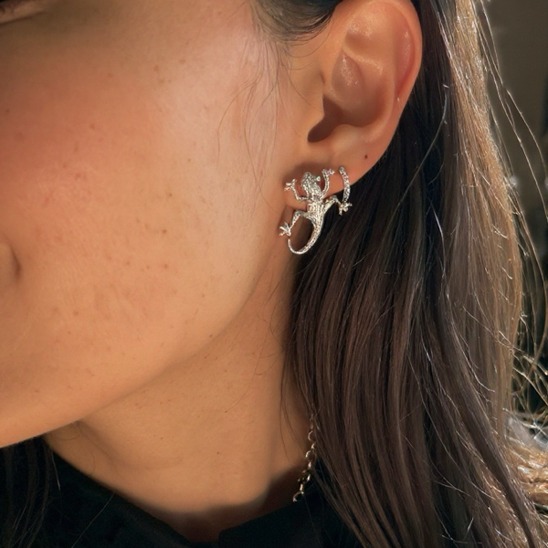 Close-up of a person wearing a silver lizard-shaped earring.