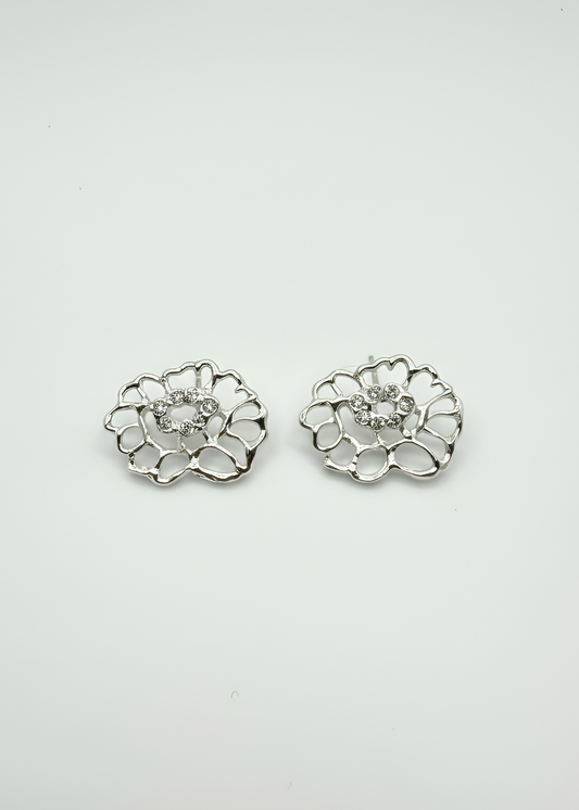 A pair of silver-toned lace flower-shaped stud earrings with a clear central gemstone, displayed on a clean white background.