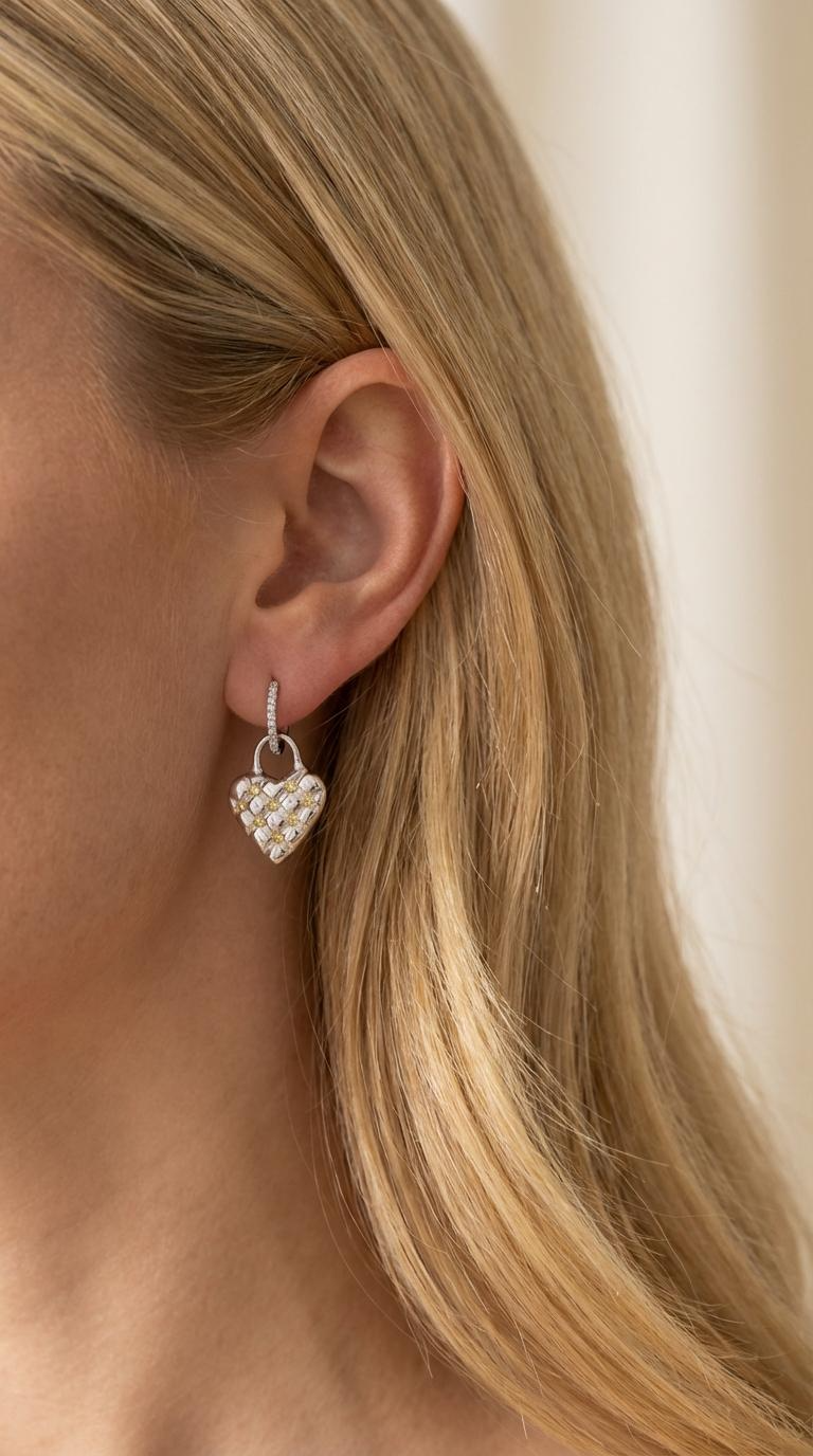 Heart-shaped earring worn by a person with blonde hair.