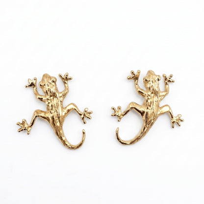 A pair of gold vermeil lizard stud earrings on a plain white background. From a jewellery store in Amsterdam.