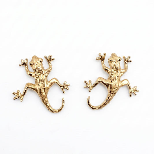 A pair of gold vermeil lizard stud earrings on a plain white background. From a jewellery store in Amsterdam.