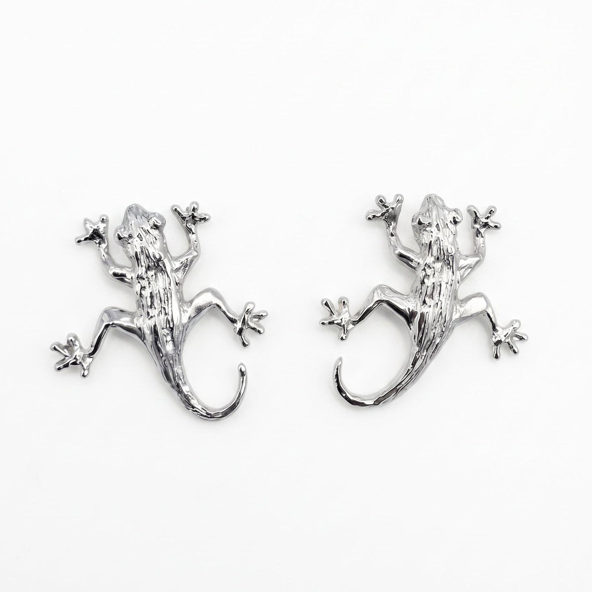 A pair of sterling silver lizard stud earrings on a plain white background. From a jewellery store in Amsterdam.