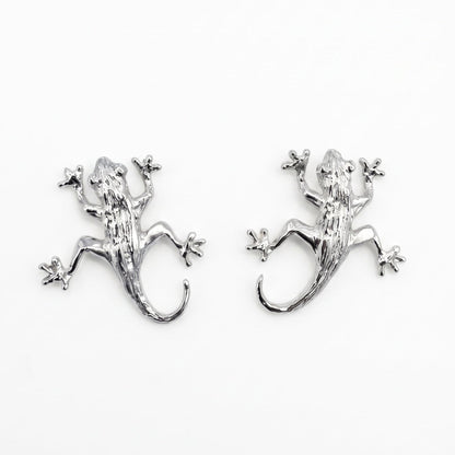 A pair of sterling silver lizard stud earrings on a plain white background. From a jewellery store in Amsterdam.