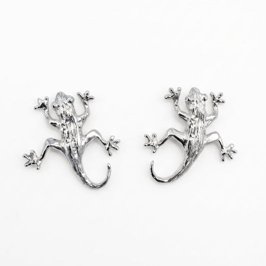 A pair of sterling silver lizard stud earrings on a plain white background. From a jewellery store in Amsterdam.