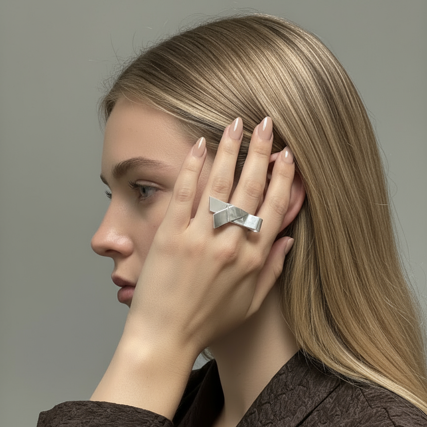 Woman wearing a silver bow ring on her hand against a neutral background