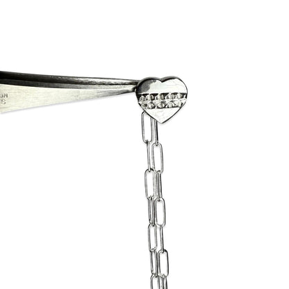 Close-up of a silver heart-shaped pendant on a chain with a white background