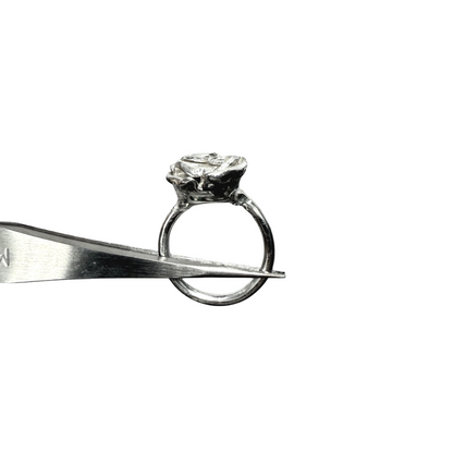 Silver rose ring being held by tweezers on a white background