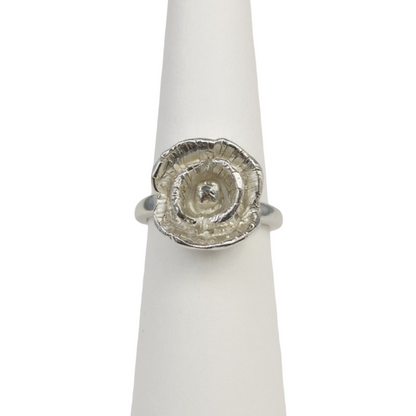 Silver ring with a textured poppy flower design on a white stand
