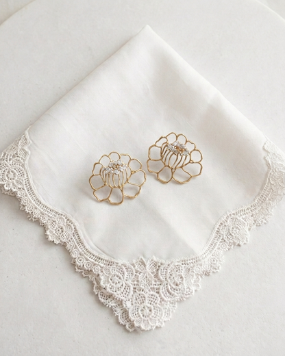 A pair of gold-tone lace flower-shaped earrings with clear moissanite gemstones at the center, displayed on a clean white background.